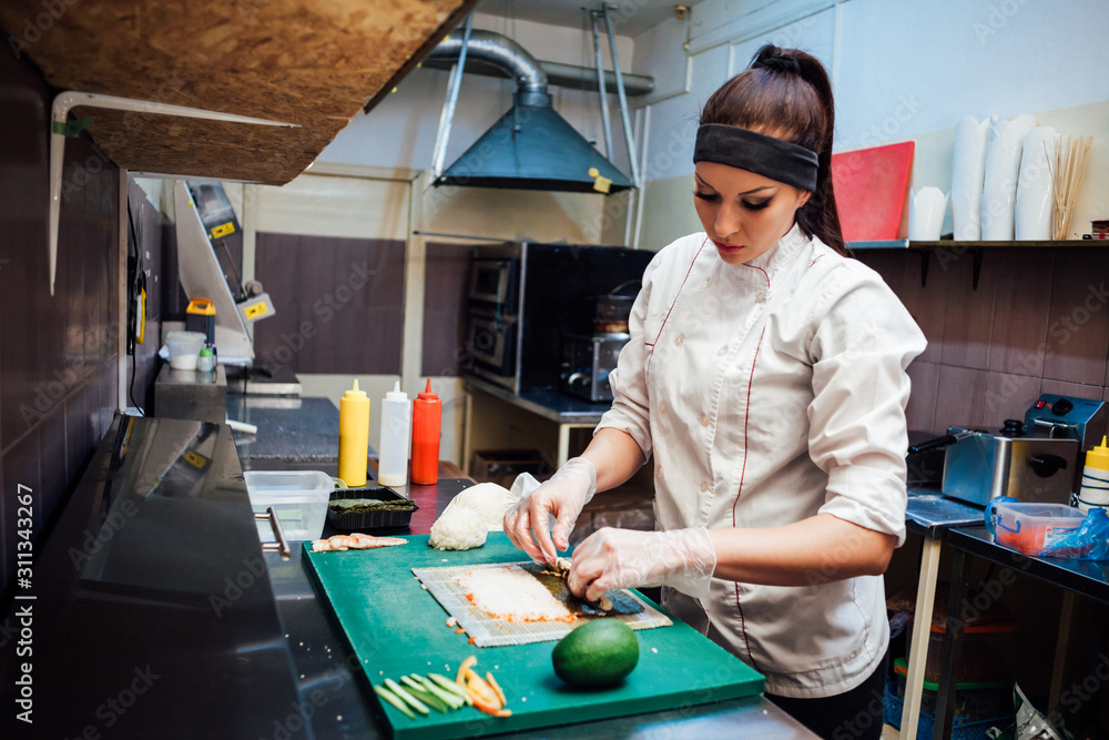 woman chef prepares fresh sushi in the kitchen of the restaurant woman chef prepares fresh sushi in the kitchen of the restaurant