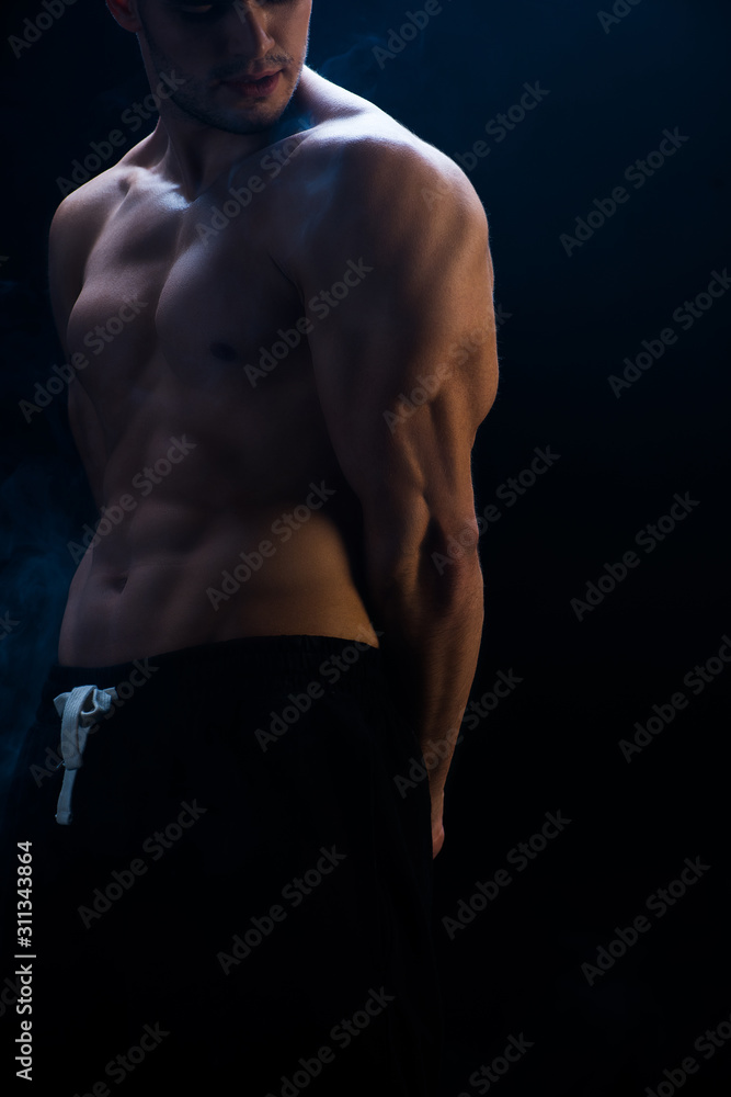 cropped view of sexy muscular bodybuilder with bare torso on black background cropped view of sexy muscular bodybuilder with bare torso on black background