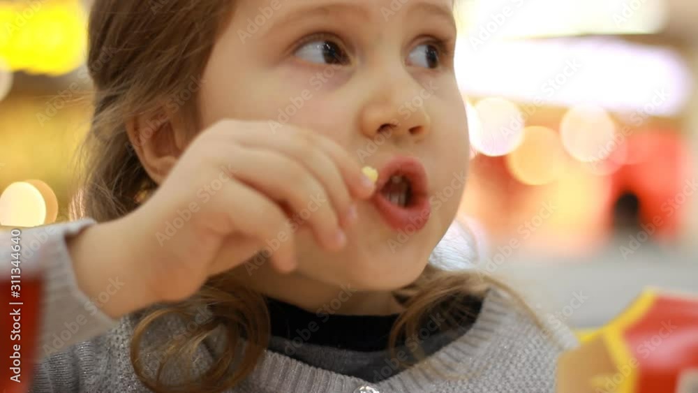 Child girl eating fast food french fries in a cafe. Portrait closeup. Child girl eating fast food french fries in a cafe. Portrait closeup.