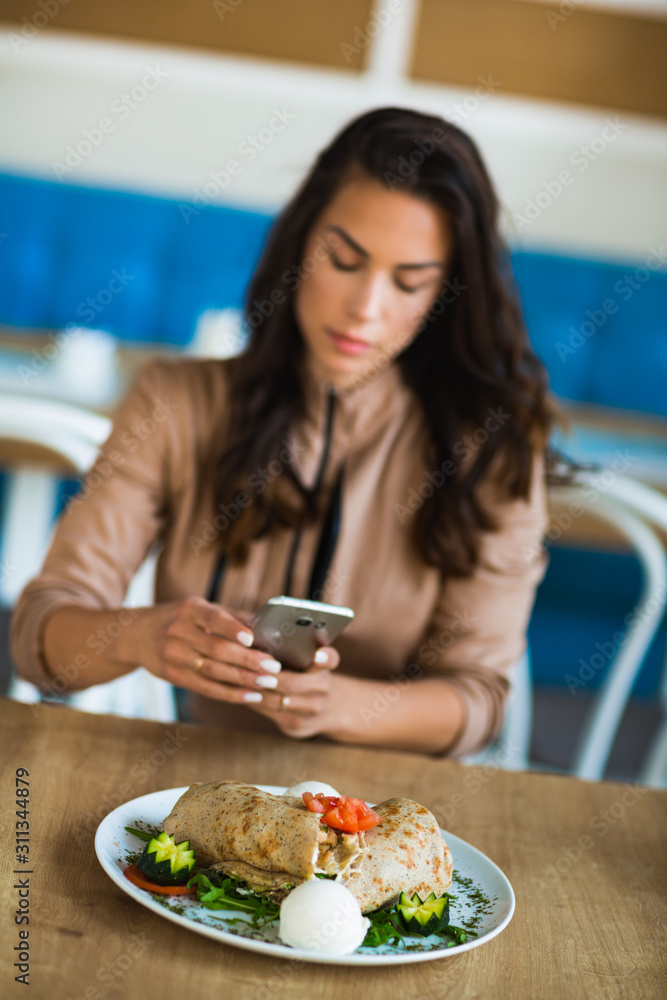 Female food blogger taking photos for their food blog using mobile phones