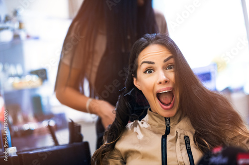 Hairdresser making hairstyle to cute lovely beautiful woman in beauty salon