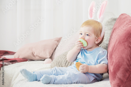 beautiful little boy in rabbit ears with easter eggs on the couch
