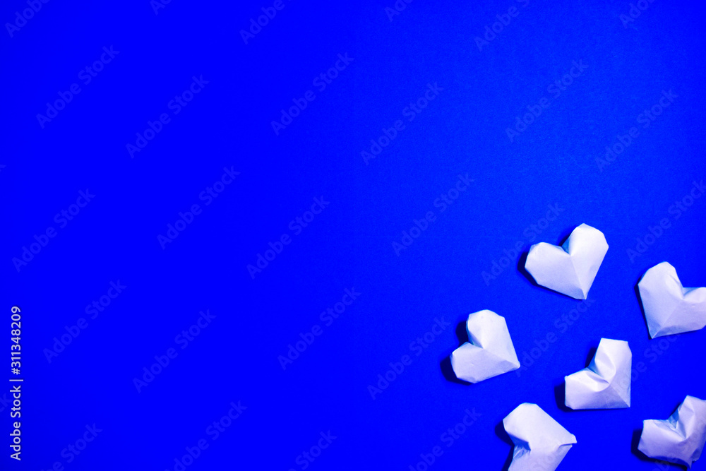 The Background Of Valentine's Day. White origami paper hearts on a blue background. The Concept Of Valentine's Day. Flat lay. Top view, copy space. The Background Of Valentine's Day. White origami paper hearts on a blue background. The Concept Of Valentine's Day. Flat lay. Top view, copy space.