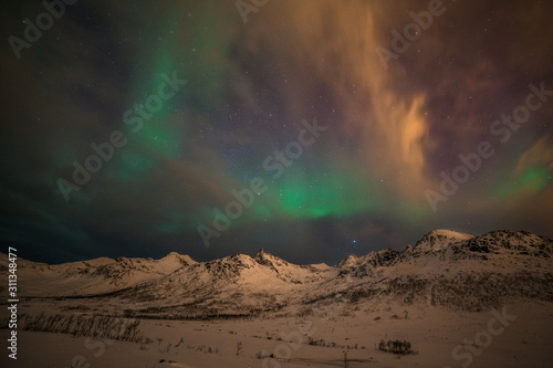 Dramatic polar lights, Aurora borealis with many clouds and stars on the sky over the mountains in the North of Europe - Tromso, Norway.long shutter speed. © Tatiana