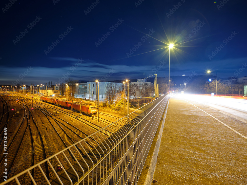 Railway engines on an illuminated freight yard, with multiple railway tracks, in an industrial area, under a starry sky Railway engines on an illuminated freight yard, with multiple railway tracks, in an industrial area, under a starry sky