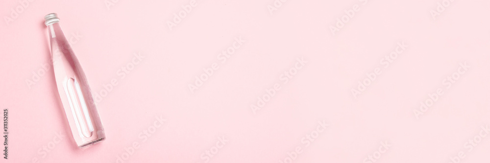 Glass bottle with clear water on a pink background. Concept of health care, water balance, beauty and health. Banner. Flat lay, top view Glass bottle with clear water on a pink background. Concept of health care, water balance, beauty and health. Banner. Flat lay, top view