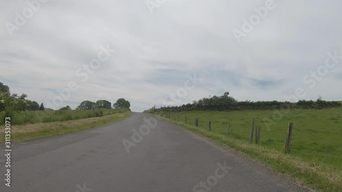 Vehicle point of view shot while driving on the road on an asphalted rural road located in Auvergne, France. The environmental soud is present. photo