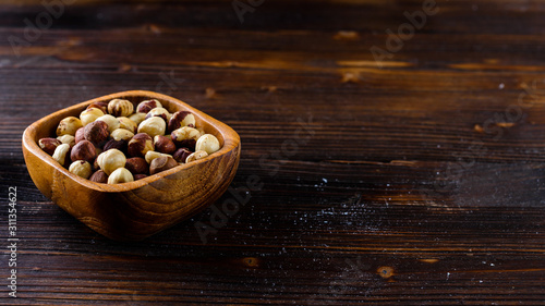 hazelnuts in a wooden bowl on a wooden background