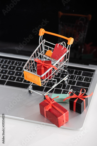 Selective focus of toy gift boxes in cart on laptop on table