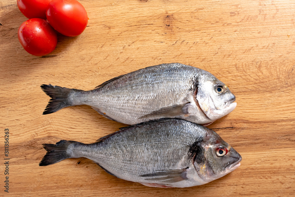 Fresh raw dorado fish with spices. Ingredients for cooking or grill on cutting board. Top view, copy space Fresh raw dorado fish with spices. Ingredients for cooking or grill on cutting board. Top view, copy space