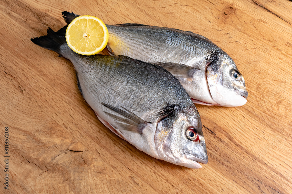 Fresh raw dorado fish with spices. Ingredients for cooking or grill on cutting board. Top view, copy space Fresh raw dorado fish with spices. Ingredients for cooking or grill on cutting board. Top view, copy space