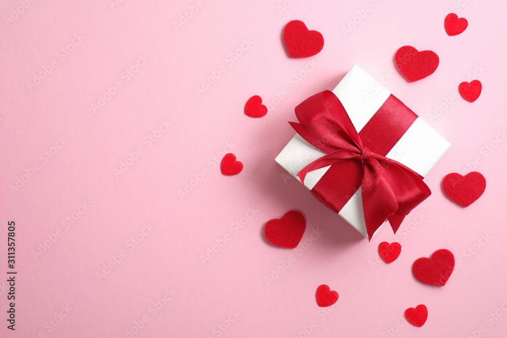 Happy Valentine's Day card mockup. White gift box with red ribbon bow and red hearts on pink background. Valentine's, anniversary, mother's day and birthday greeting. Flat lay, top view, overhead.