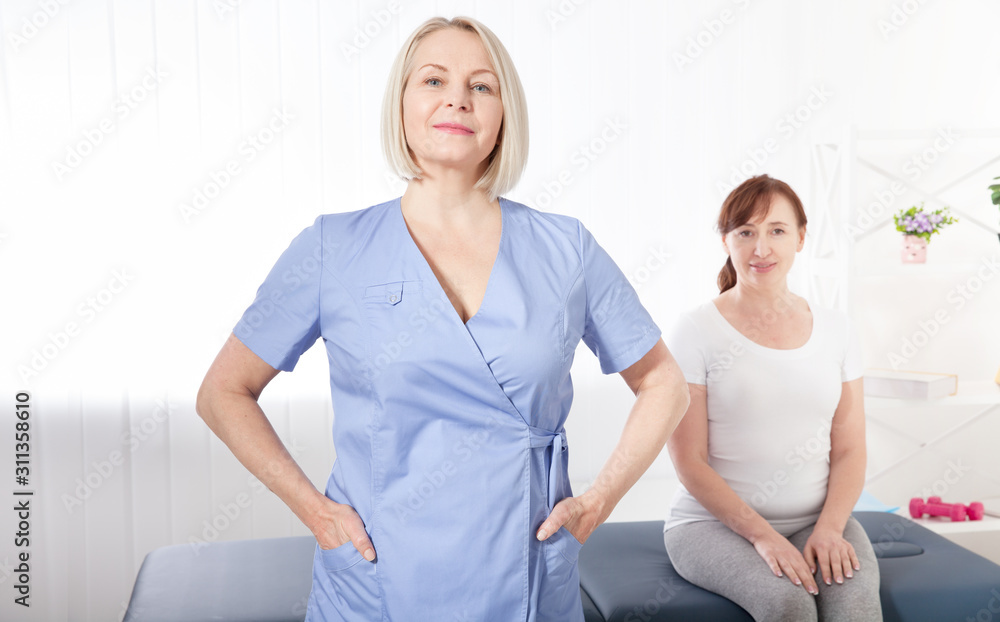 Obraz premium Physiotherapist smiling at camera in medical office