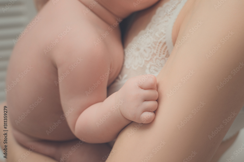 Children's hand close-up. Mother with a baby in her arms. Moment of tenderness.