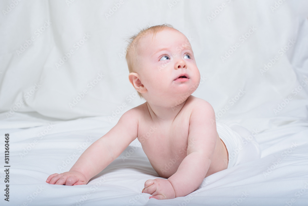 Baby on her tummy. Looking up with surprised expression. White background Baby on her tummy. Looking up with surprised expression. White background