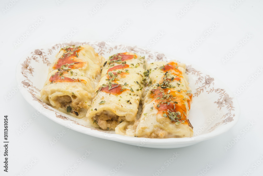 Canelones (cannelloni) with meat filled pasta and cheese and tomato on a plate Canelones (cannelloni) with meat filled pasta and cheese and tomato on a plate