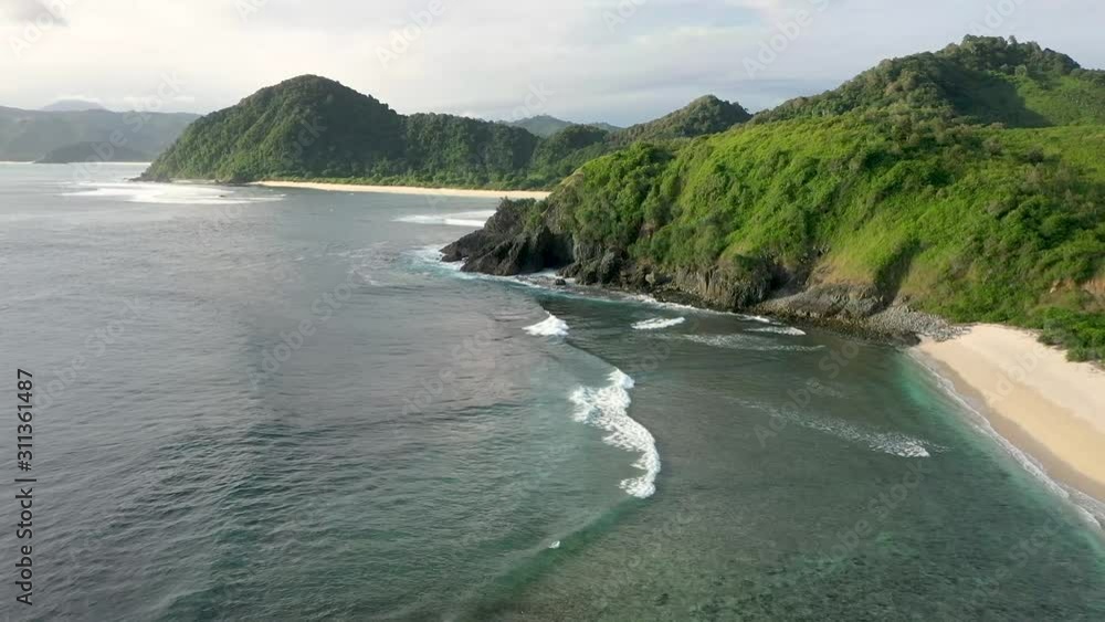Gently foamy waves washing on the white sandy beach, Pantai Beach, Semeti , Lombok, Bali, Indonesia, Aerial drone establishing shot Gently foamy waves washing on the white sandy beach, Pantai Beach, Semeti , Lombok, Bali, Indonesia, Aerial drone establishing shot