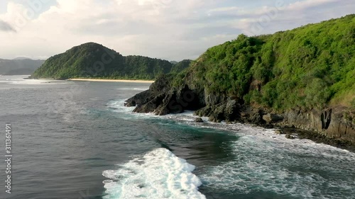 Breathtaking beauty of the foamy waves crashing on the rocky shore. Drone shot revealing white sand beach behind the cliffs. Pantai Mawi, Semeti beach, Lombok, Bali, Indonesia photo