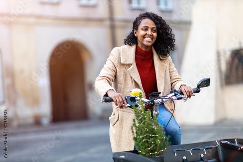 Young woman with small Christmas tree in a cargo bike