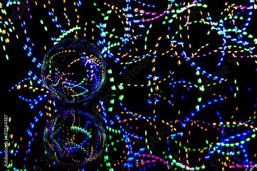 brilliant view of long exposure light painting experiment with lens ball placed over glass for reflection using a tripod inside a complete dark room for Christmas festival celebration