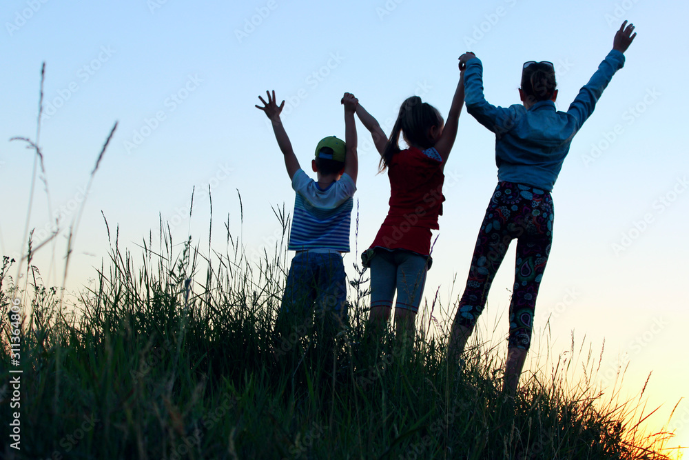 Blurry image of children standing in a clearing holding hands up. Kids outdoors. People, children, childhood and family concept. Blurry image of children standing in a clearing holding hands up. Kids outdoors. People, children, childhood and family concept.