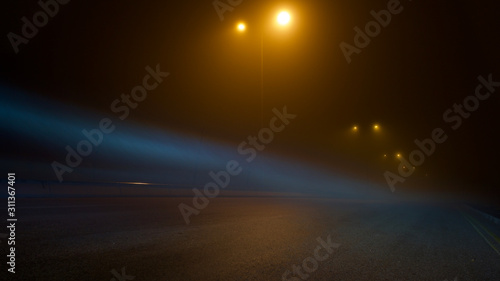 road lighting poles and car headlight on a foggy night