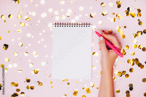 Female hands holding notebook with empt copy space on festive confetti background.