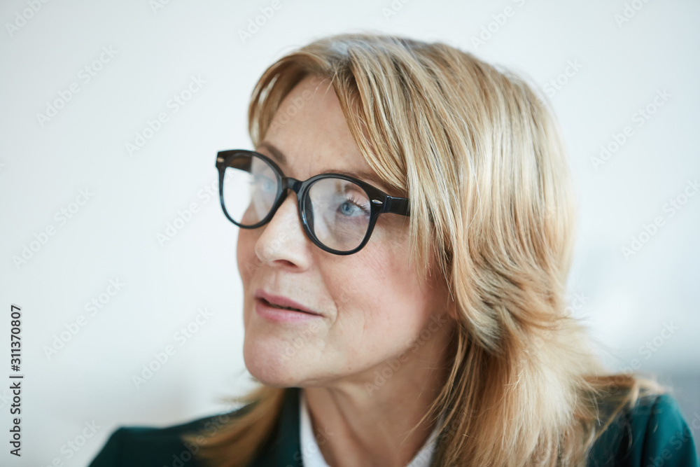 Beautiful mature woman in eyeglasses with blond hair looking away with pensive sight isolated on white background