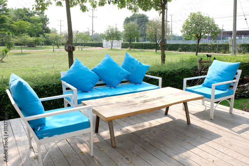 set of wooden coffee table with the blue chairs at the terrace near by the garden.