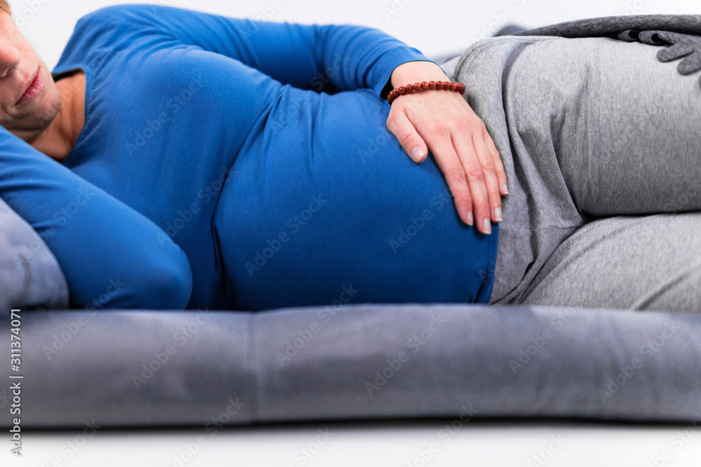 Pregnant tired exhausted woman with stomach issues at home on a couch, being sick. - obrazy, fototapety, plakaty 