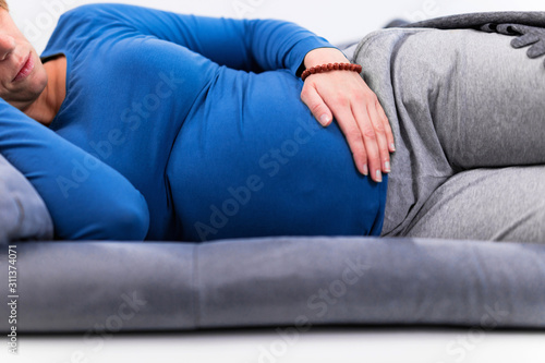 Pregnant tired exhausted woman with stomach issues at home on a couch  being sick.