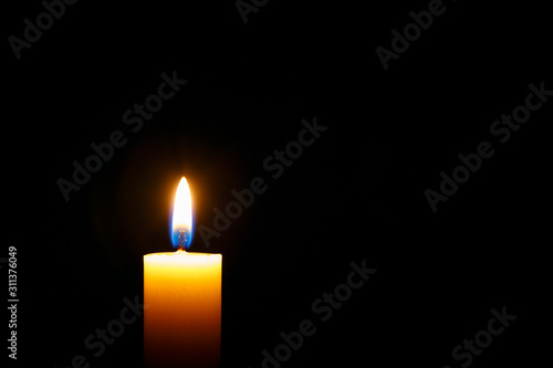 Burning candle on black background,space for text