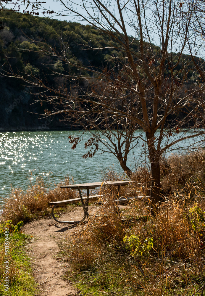 Picnic Table Sits in Autumn Fall Sunshine Near Waters Edge Picnic Table Sits in Autumn Fall Sunshine Near Waters Edge