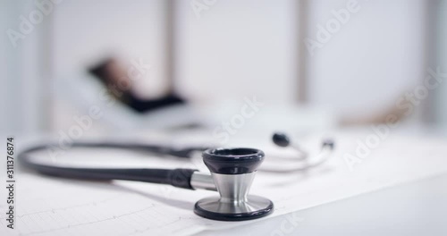 Closeup of stethoscope on the electrocardiogram (EKG). Doctor and Patient blurred background. Tracking shot