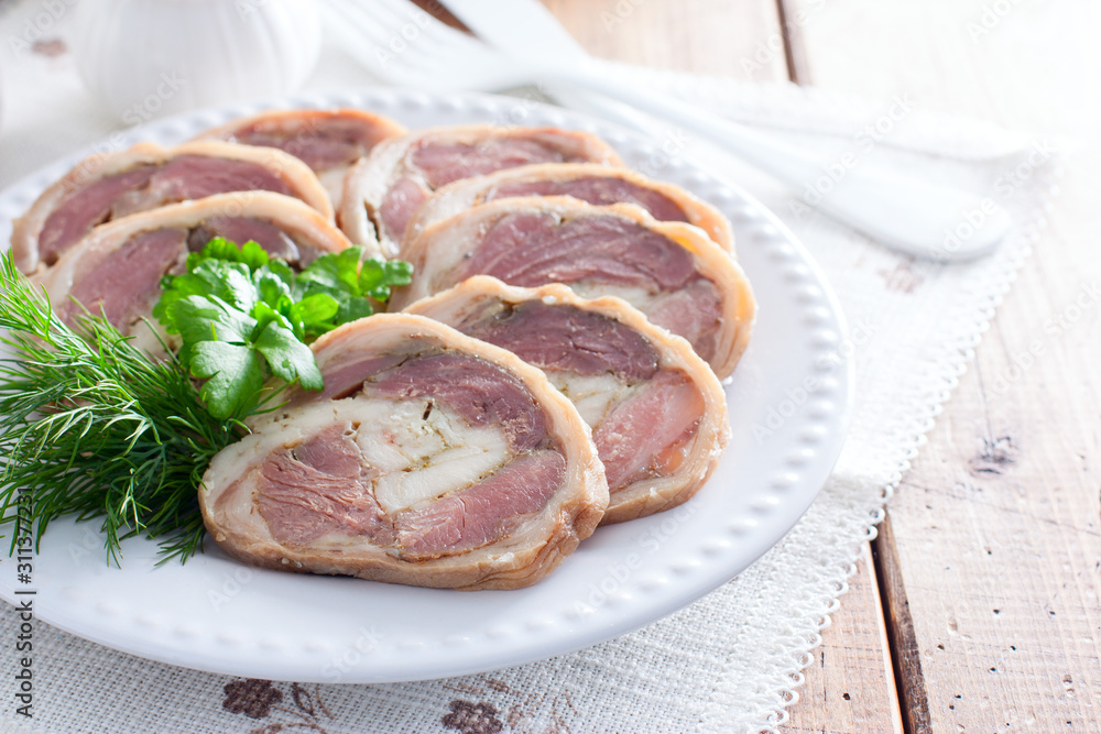 Cooked pork knuckle roll with chicken on a white plate, horizontal Cooked pork knuckle roll with chicken on a white plate, horizontal