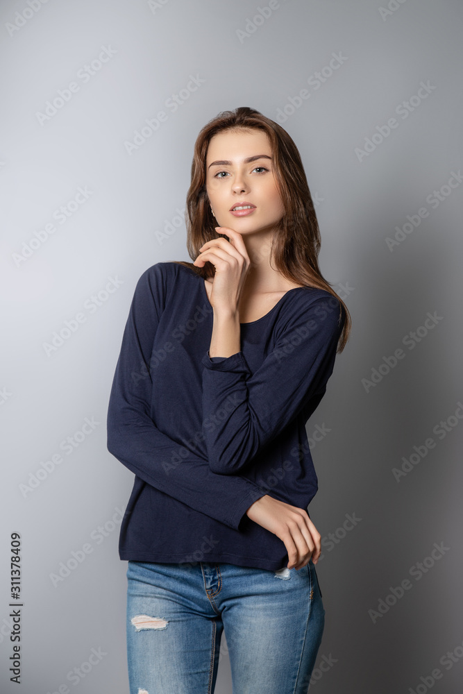 young beautiful girl with long brown hair. The hand near the chin. The girl looks at the camera. young beautiful girl with long brown hair. The hand near the chin. The girl looks at the camera.