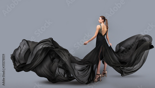 beautiful young girl in flying black dress. Flowing fabric. Light black fabri...