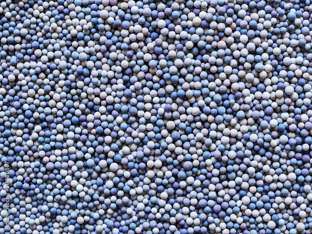 A lot of tiny ceramic balls or granules in color range from beige to dark blue as a background. Grainy or granular texture. A lot of tiny ceramic balls or granules in color range from beige to dark blue as a background. Grainy or granular texture.