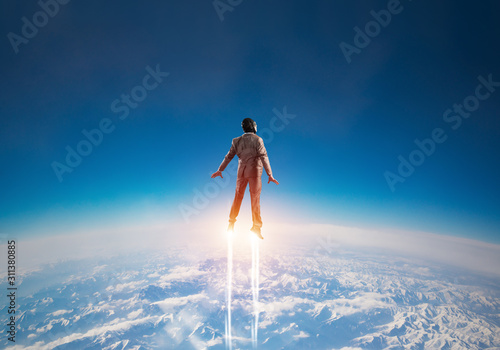 Photographie Businessman in suit and aviator hat flying in sky