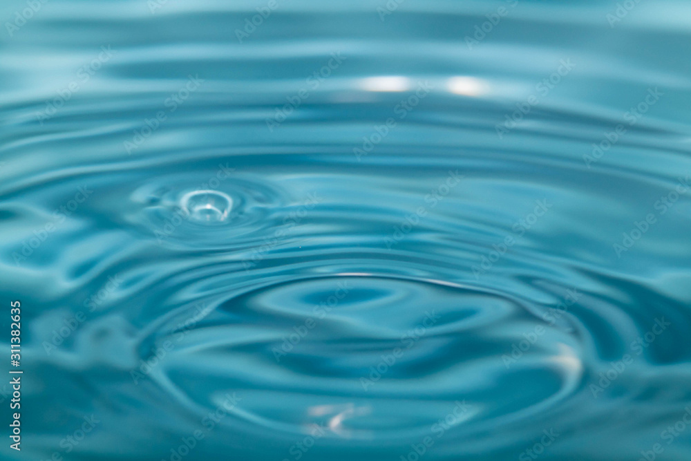 Closeup Water drop falling on the surface of the water and beautiful circular wave ripple, fresh natural mineral water drink water concept Closeup Water drop falling on the surface of the water and beautiful circular wave ripple, fresh natural mineral water drink water concept