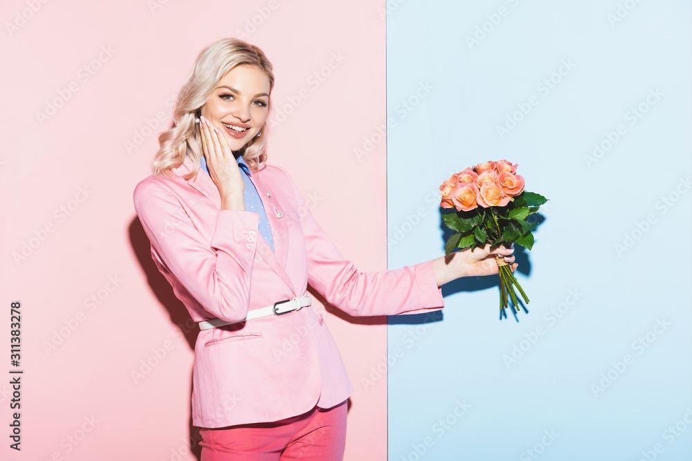 smiling woman holding bouquet on pink and blue background smiling woman holding bouquet on pink and blue background