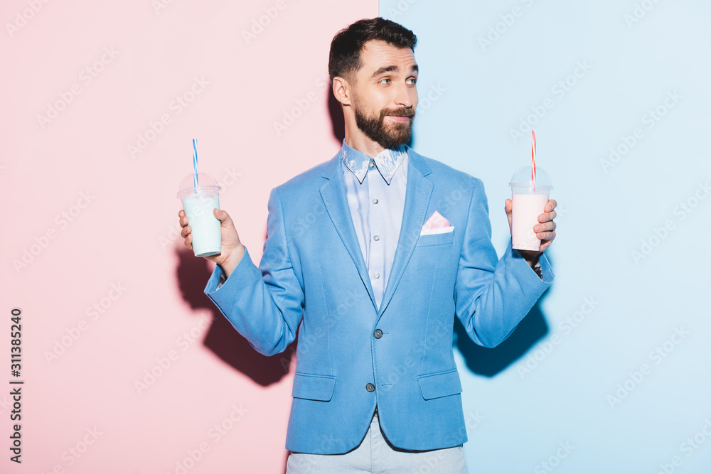 smiling man holding cocktails on pink and blue background smiling man holding cocktails on pink and blue background