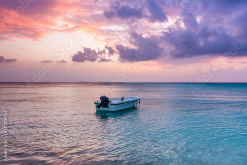 Awesome Beach sunset at Maldives island Funadhoo colorful sky with alone boat at blue sea amazing nature scenery best place to travel in the world