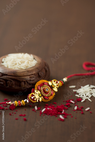 Indian festival: Raksha Bandhan background with an elegant Rakhi, Rice Grains and Kumkum. A traditional Indian wrist band which is a symbol of love between Brothers and Sisters.