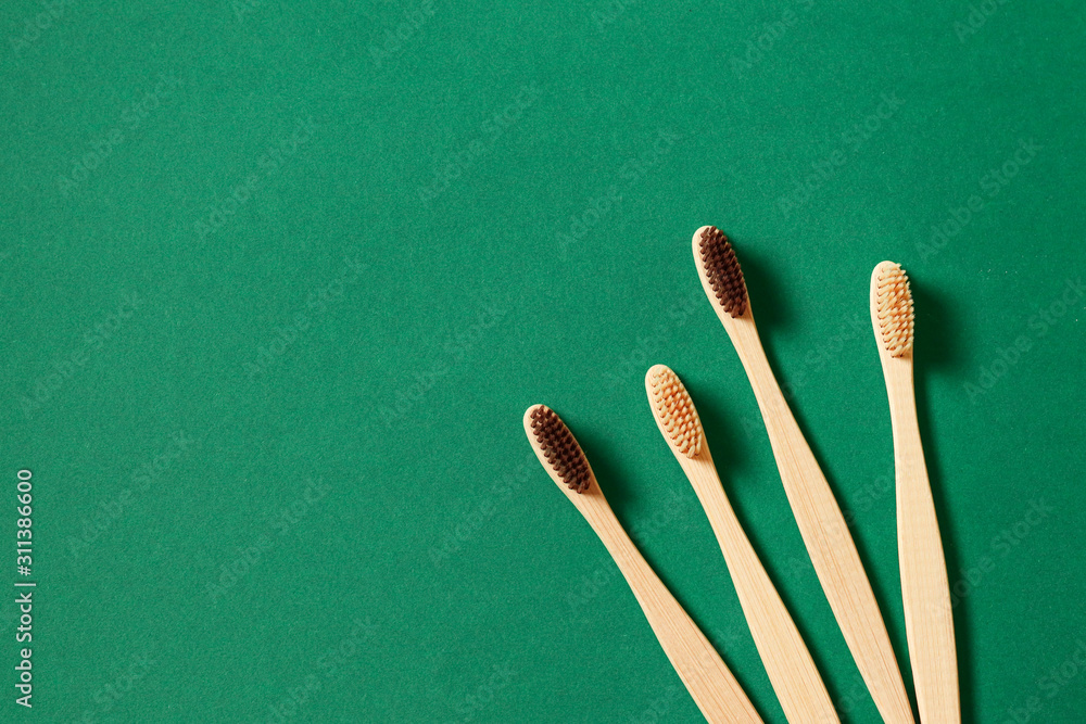 Top view or flat lay concept with eco bamboo tree toothbrushes on green background