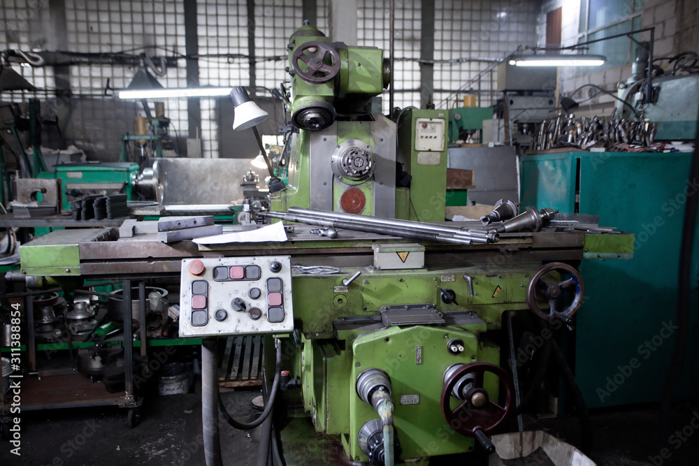 closeup of metallic lathe working against factory industrial interior background