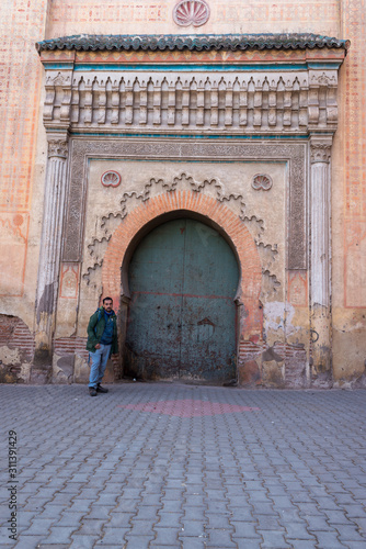 Man with green jacket next to a green arabic door