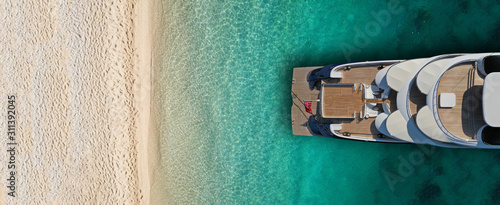 Aerial drone top view ultra wide photo of luxury yacht docked near exotic sandy turquoise beach photo