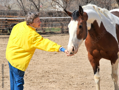 Female feeding her horse outside.