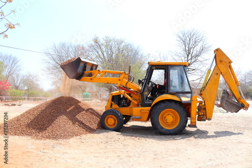 Fotografía A backhoe dumping crushed stone